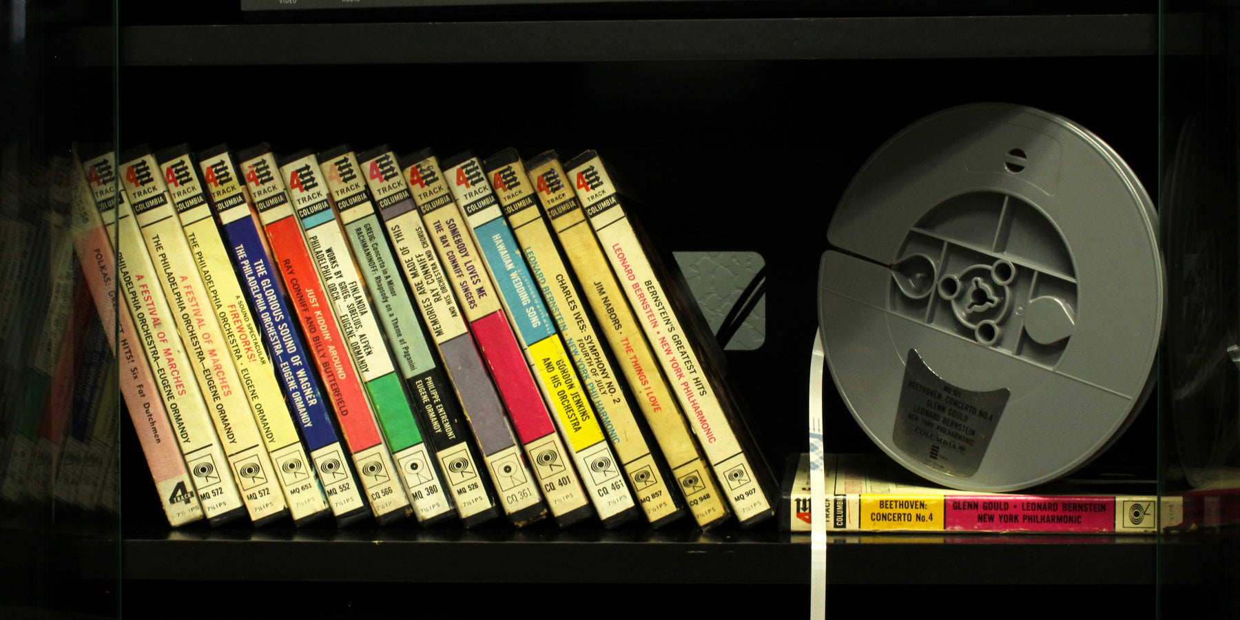 Vintage reel-to-reel tapes on a shelf